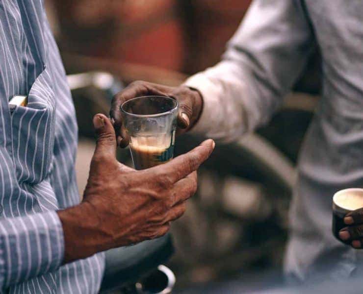 Two men are holding a glass of coffee.
