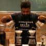 A man is making coffee in a coffee shop.