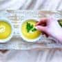 Three bowls of yellow soup with parsley on a wooden table.