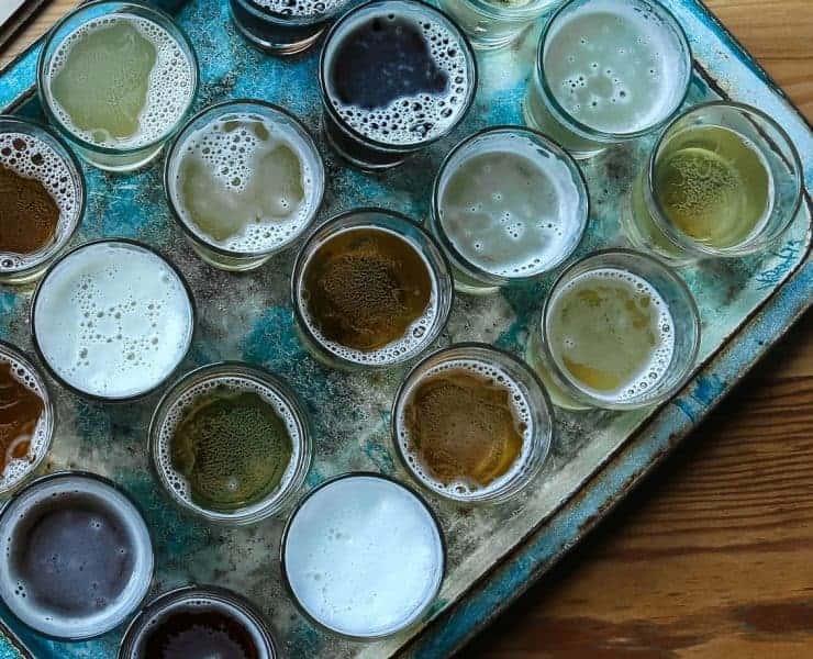 A tray of different beers on a wooden table.