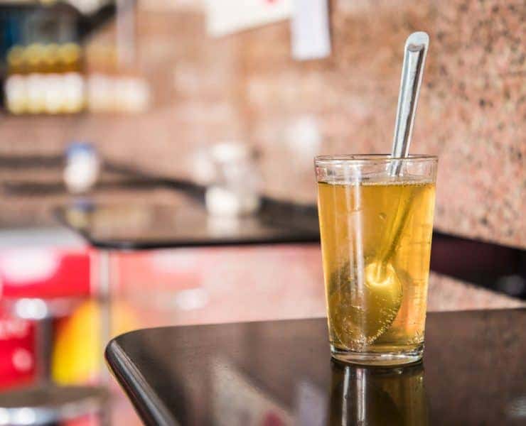 A glass of tea with a straw sitting on a counter.