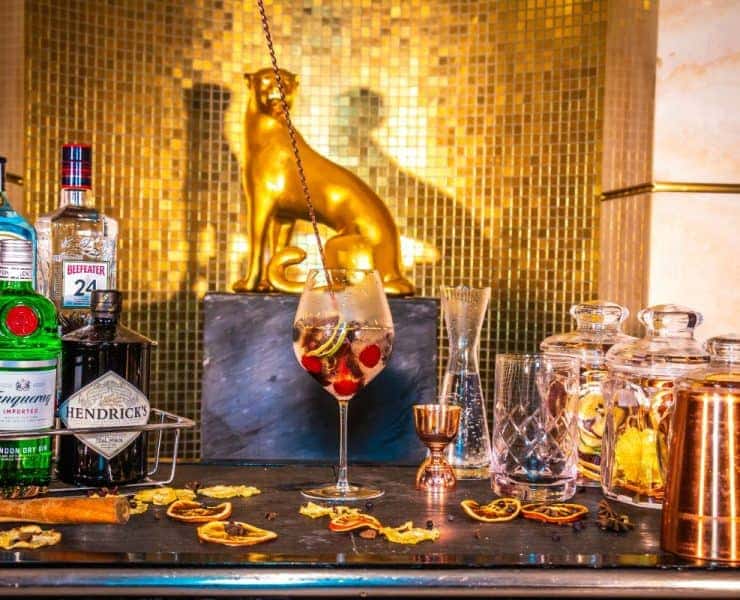 A bar with a bottle of gin and a tiger statue.