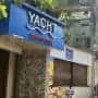 Closed restaurant named "Yacht Resto Bar" with a blue sign, located on a tree-lined street.