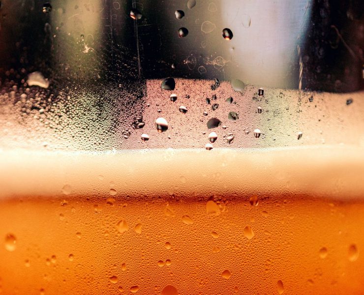 Close-up of beer in a glass, showing condensation and foam on the surface.