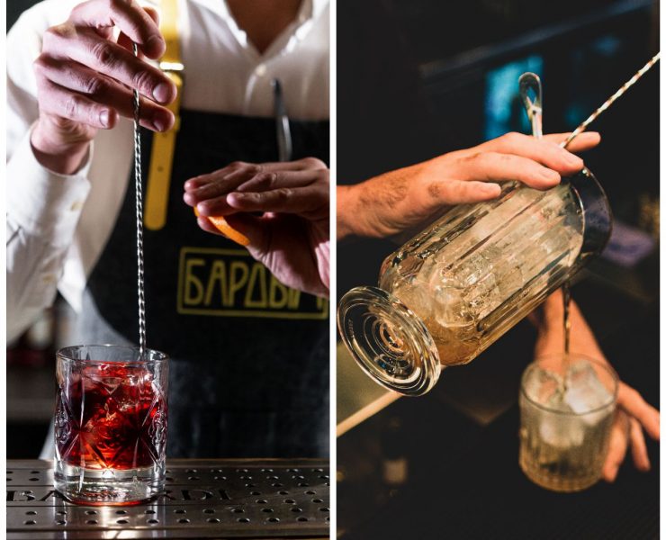 Two bartenders prepare cocktails: one stirs a red drink in a glass, and the other pours a mix from one glass to another over ice.