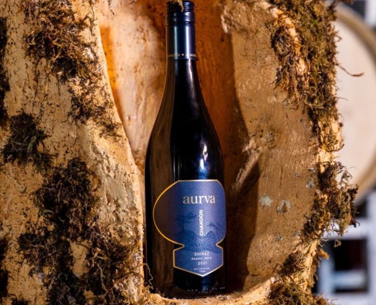 A wine bottle labeled "Aurva Chardonnay" 2022 rests in a natural alcove lined with moss.